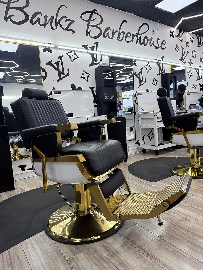 A gold and black barber chair on the floor at Bankz BarberHouse